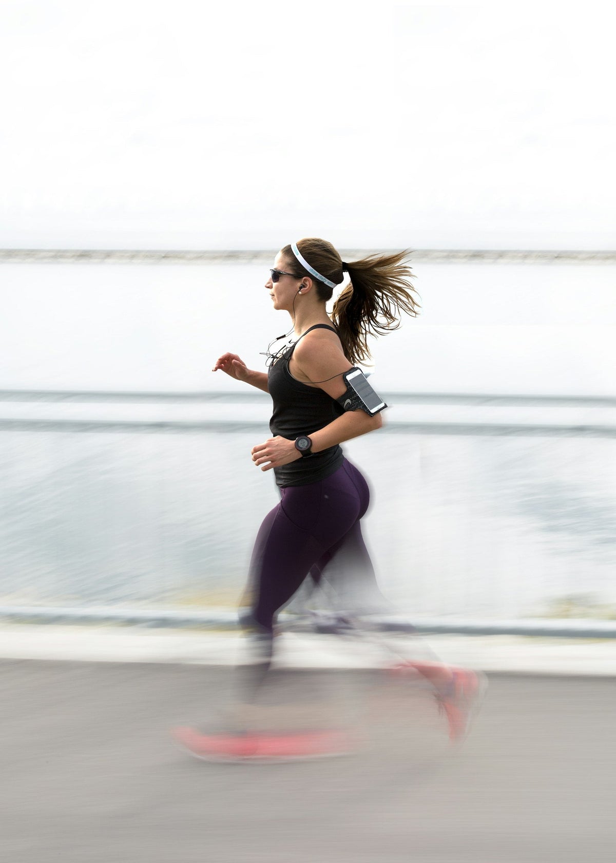 Woman running outdoors with her phone in an armband, the setup Fitbit Air uses for connected GPS