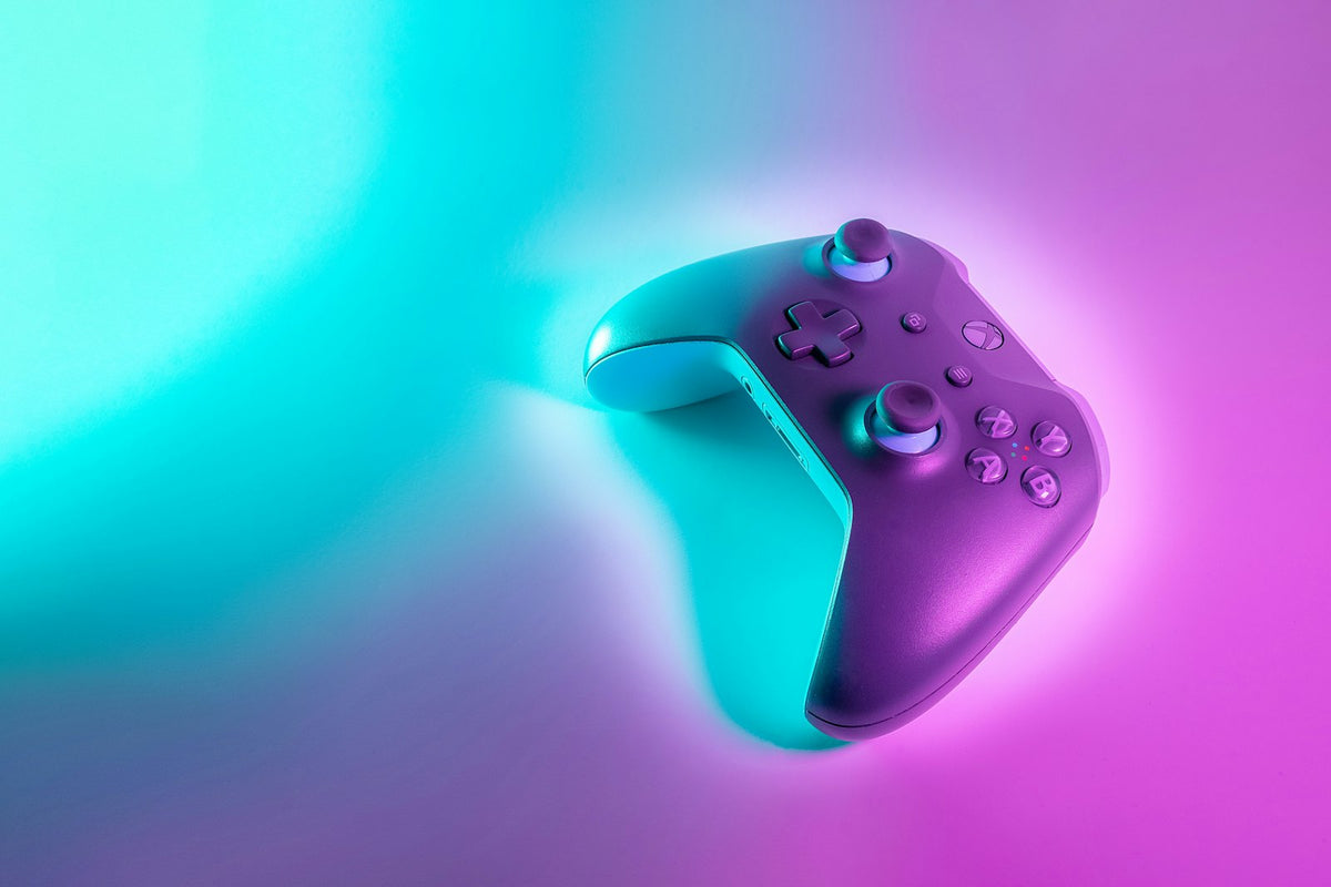 Wireless game controller lit by cyan and magenta light, gaming on Starlink in the UAE