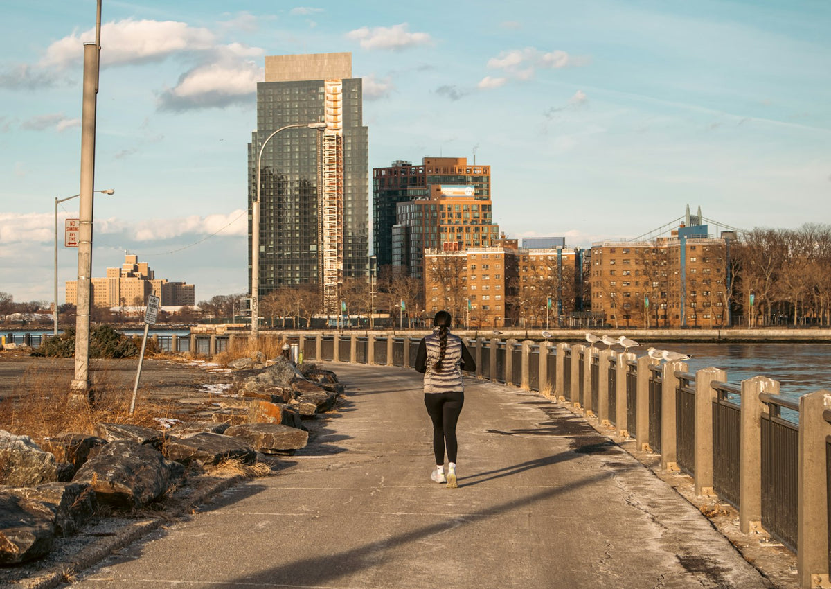 Runner jogging on a city pathway with tall buildings in the background
