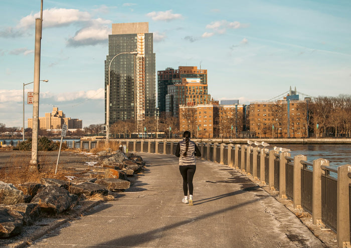 Runner jogging on a city pathway with tall buildings in the background