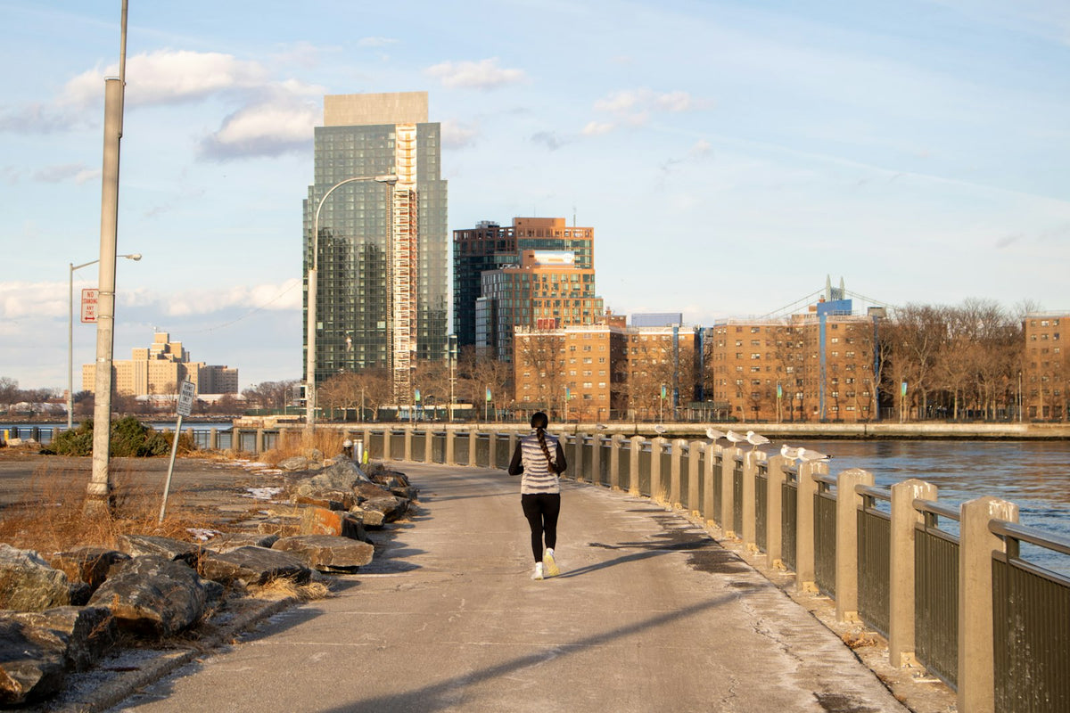 Woman running on a waterfront path in the city at sunrise